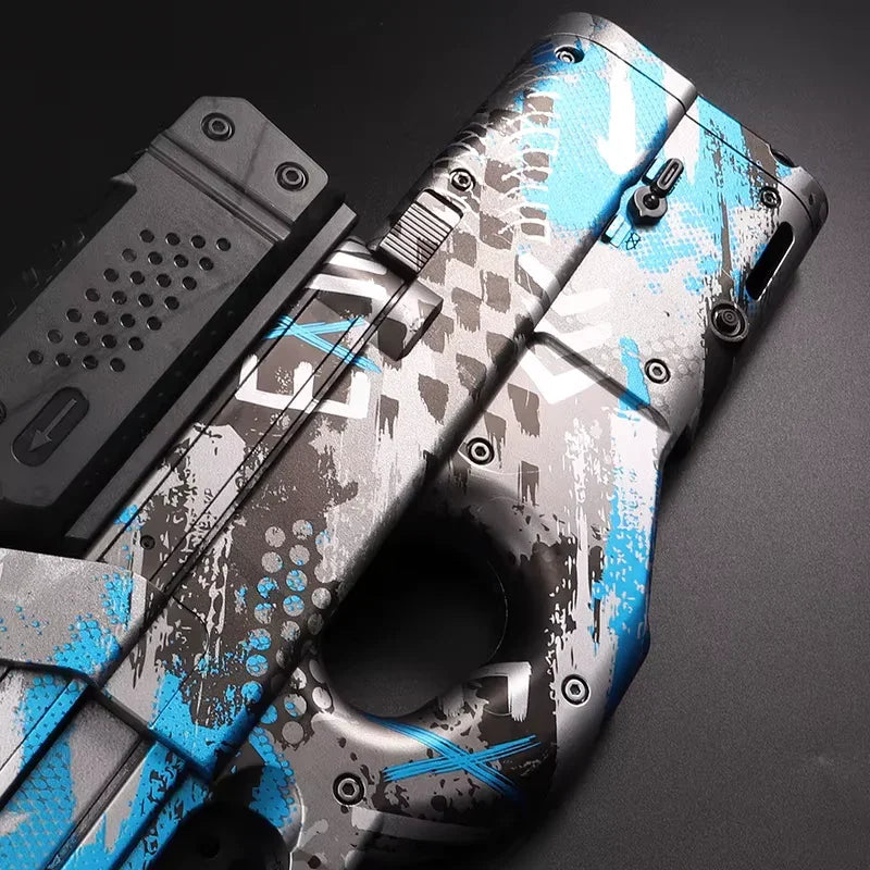 Detail pistole Gelshot P90 na gelové kuličky od společnosti gelshot.cz s vlastním modrým, bílým a šedým maskovacím nátěrem na černém pozadí. Pozornost je zaměřena na její horní část, kde je zvýrazněn detailní texturovaný design.